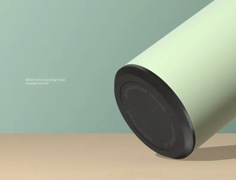 Green cylindrical container with black lid on a beige surface against a light green background