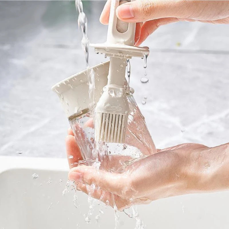 Person washing a kitchen brush under running water