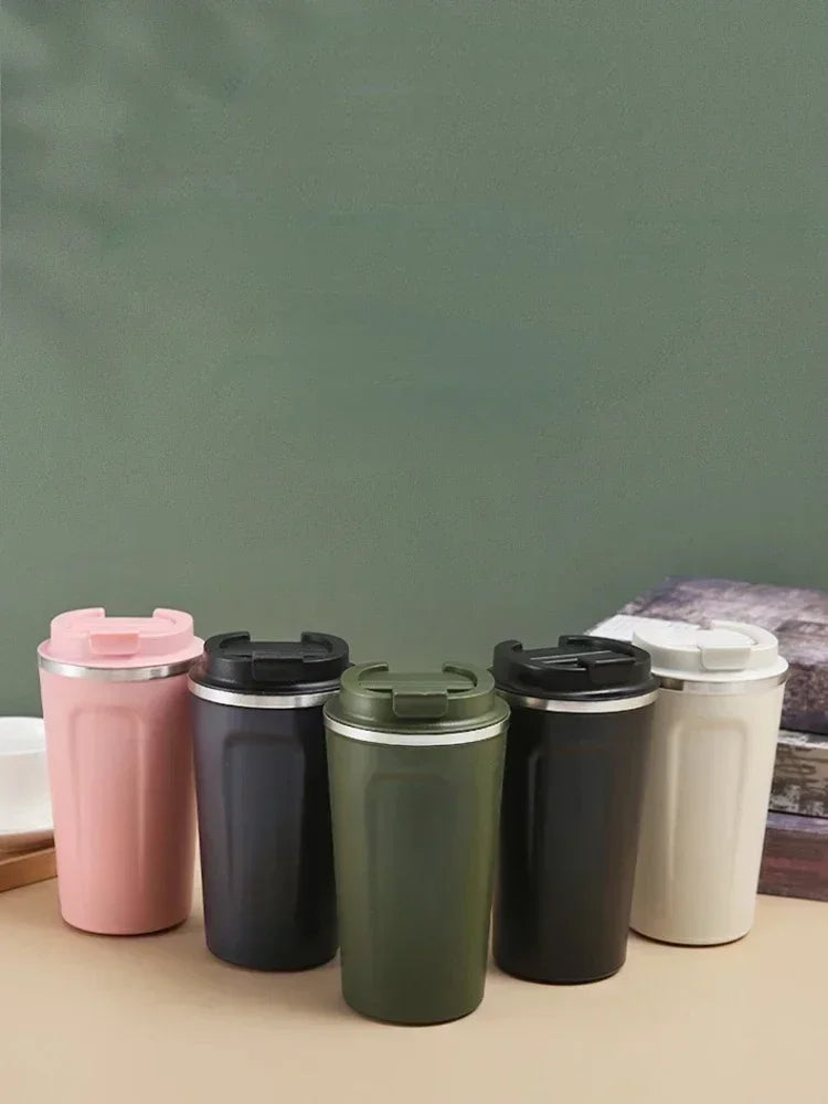 Five insulated travel mugs in different colors on a wooden surface with a green chalkboard background.