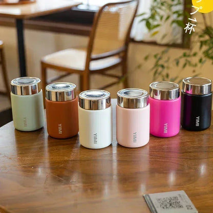 Set of colorful thermos bottles on a wooden table with a blurred indoor background