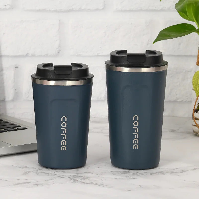 Two blue insulated travel mugs with black lids on a marble surface.