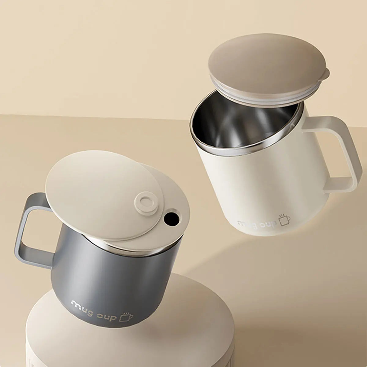 Two insulated mugs with lids on a beige background
