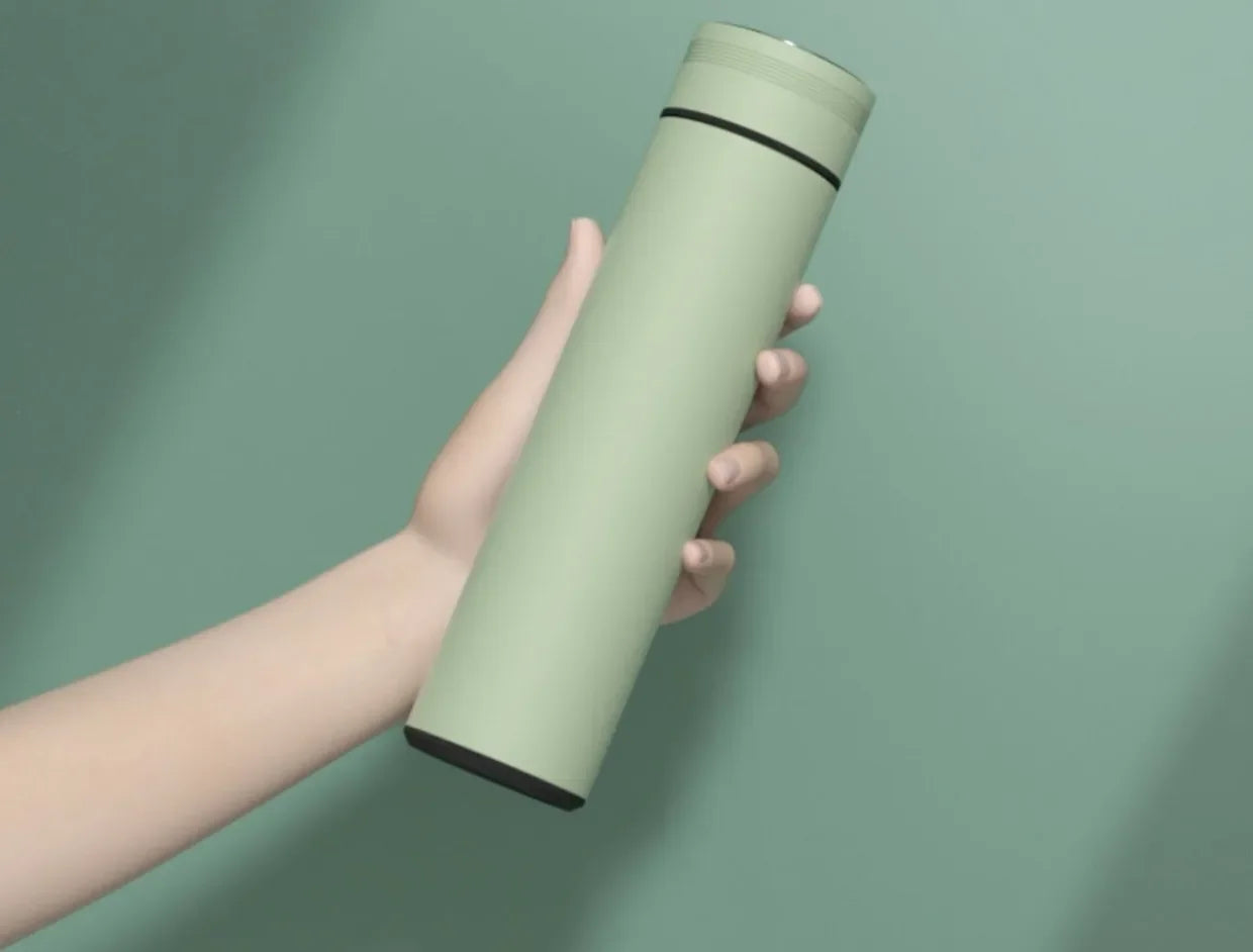 Hand holding a green thermos against a green background