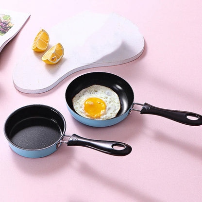 Two small frying pans with a fried egg on a pink surface