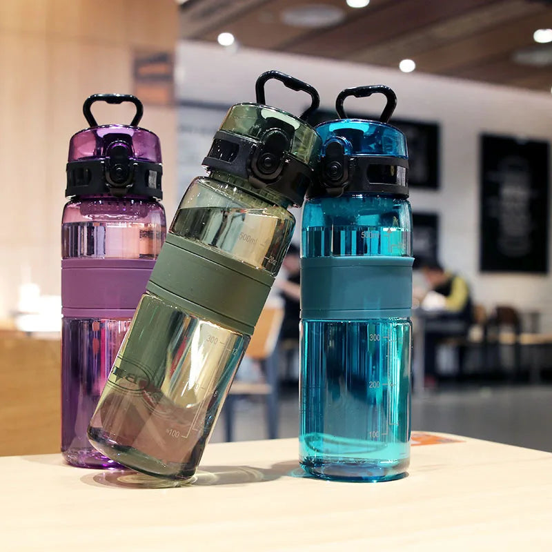 Three colorful water bottles on a table with a blurred indoor background