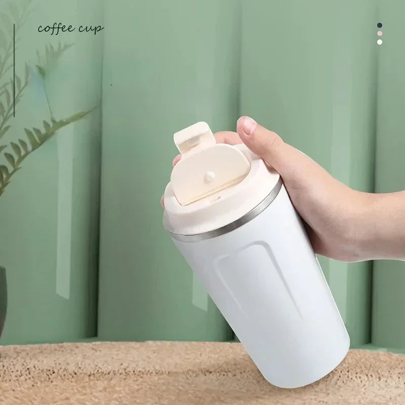 Hand holding a white coffee cup with a lid against a green background